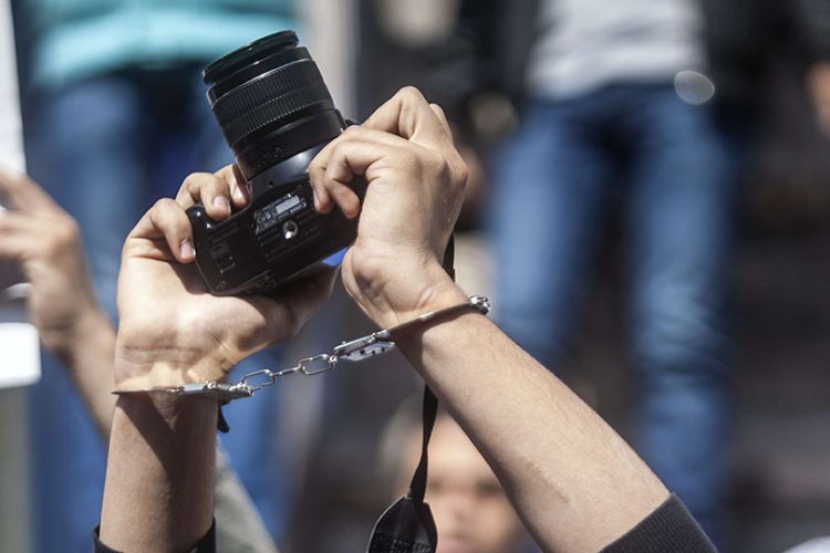 A photojournalists with his mouth tapped holds up his camera as he demonstrates with fellow colleagues in front of the journalist's syndicate in Cairo against repeated attacks on members of the press in Egypt on April 4, 2014. AFP PHOTO / MAHMOUD KHALED